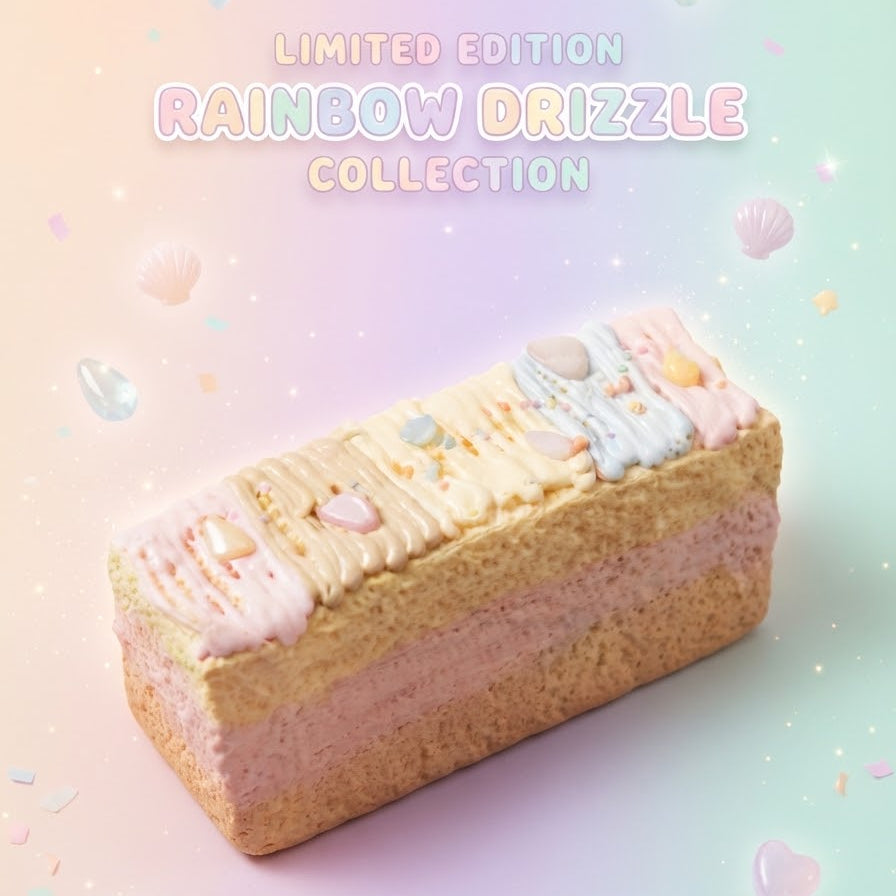 A rectangular frosted pastry or cake slice with pastel pink, cream, and light blue icing, decorated with small candy-like toppings and sprinkles, set on a soft pastel gradient background with floating bubbles and the text 'LIMITED EDITION RAINBOW DRIZZLE COLLECTION'.