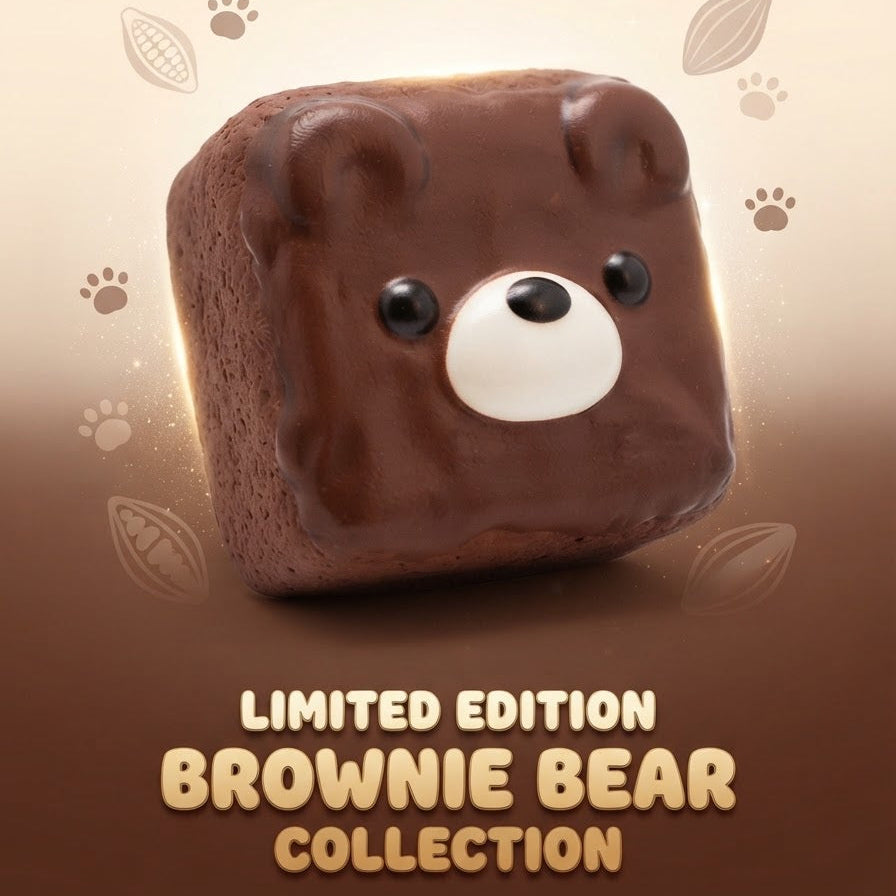 A square brownie styled like a bear face, with glossy chocolate brown frosting, small black eyes, and a white snout. The image includes decorative paw prints and cookie motifs on a beige-to-brown gradient background, with the text 'LIMITED EDITION BROWNIE BEAR COLLECTION' at the bottom.