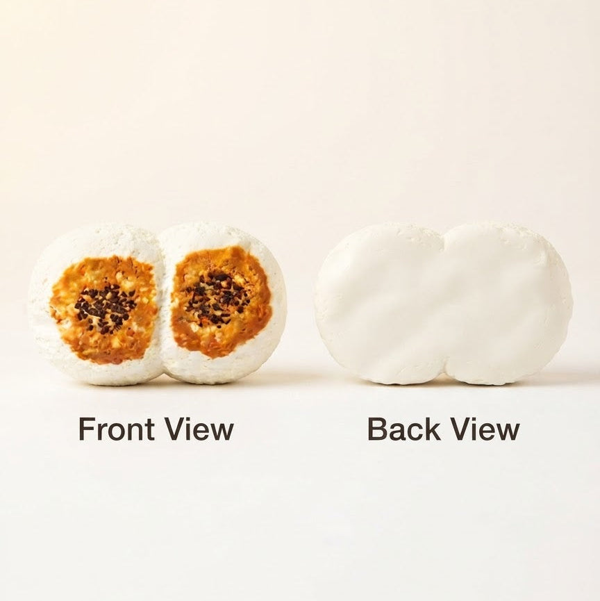 Two white mochi candy pieces shown on a plain light background with labels reading 'Front View' and 'Back View.' The front view reveals a glossy orange-brown center with dark seed-like details, while the back view shows the smooth white exterior.