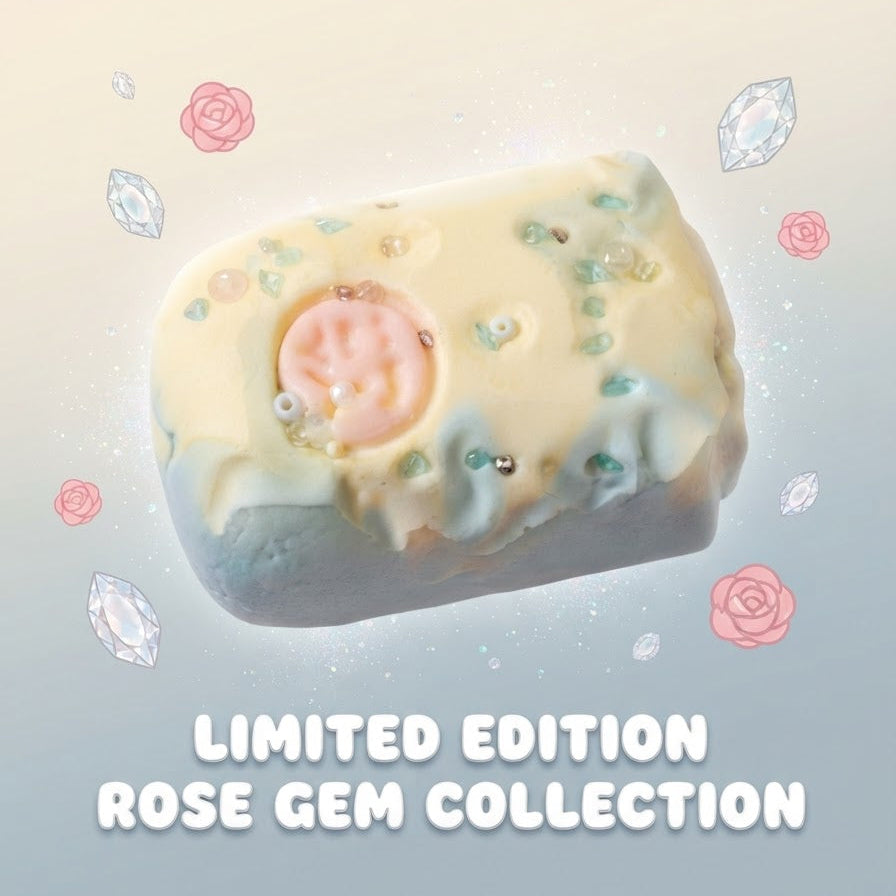 A single decorative product centered on a soft pastel background with floating gem illustrations and the text 'LIMITED EDITION ROSE GEM COLLECTION' below. The product appears to be a rectangular pale cream item with a pink circular center, small blue-green speckles, and a light blue lower edge.