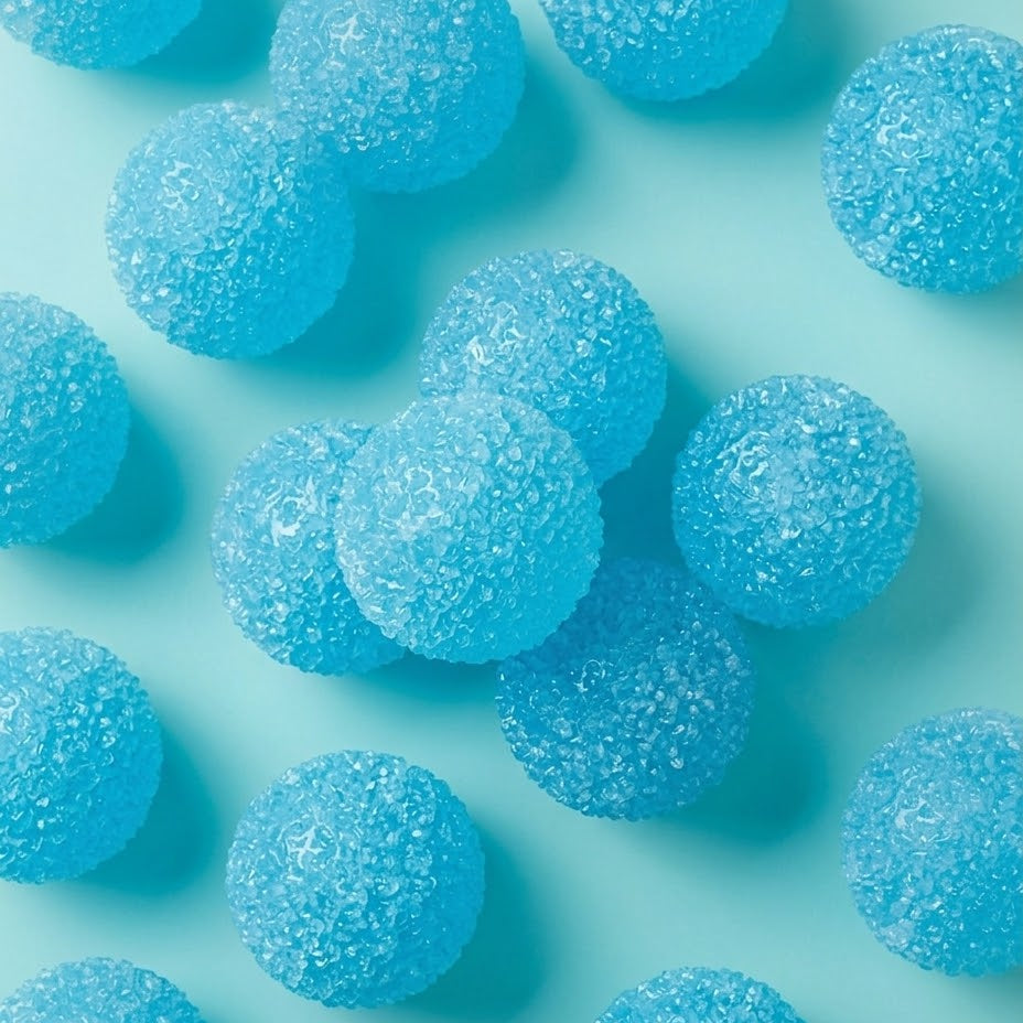 Blue sugar-coated gummy candies scattered on a light aqua background.