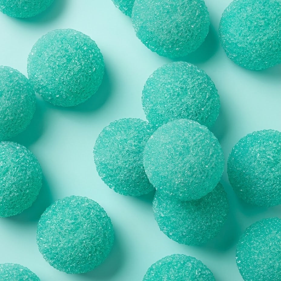 Turquoise sugar-coated gummy candies scattered on a light aqua background.