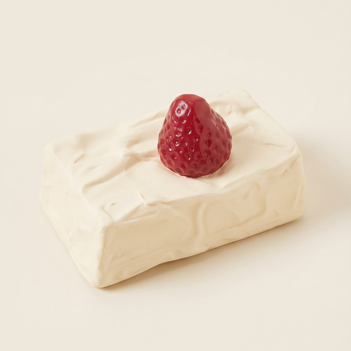 A novelty ceramic salt and pepper shaker designed to look like a block of soft white cheese topped with a small red strawberry, set against a solid cream background.