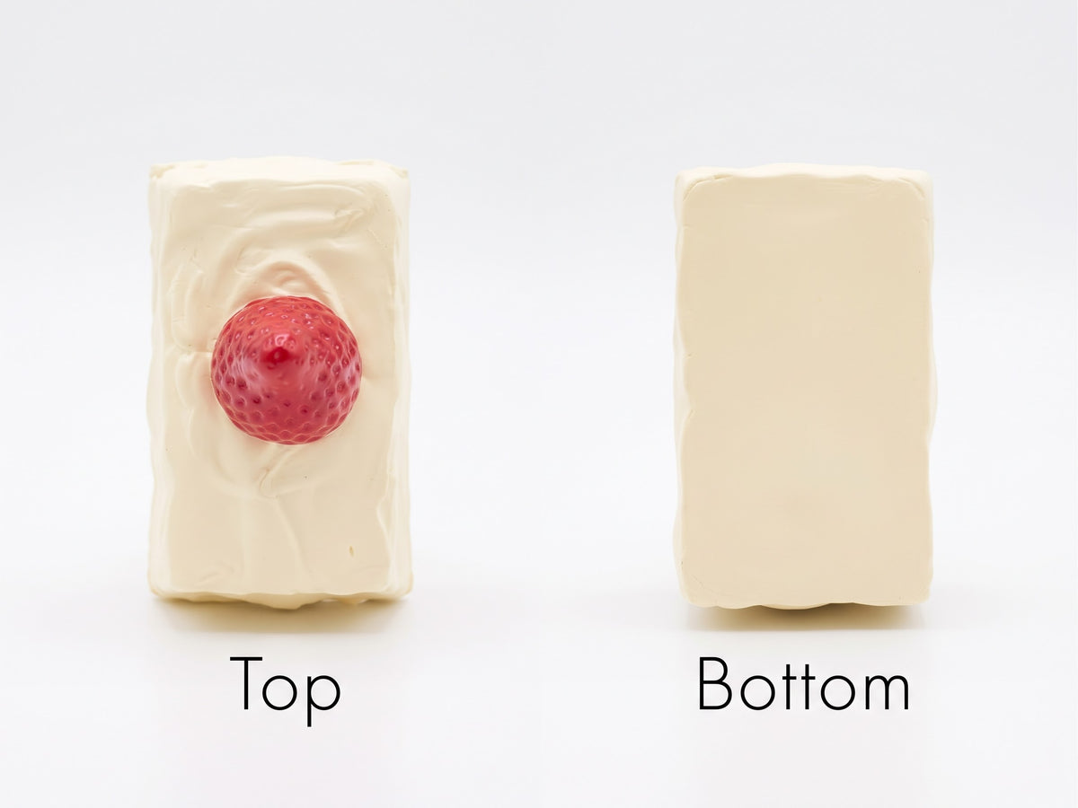 Two rectangular cream-colored soap bars on a white background, labeled 'Top' and 'Bottom'. The left bar, labeled 'Top', has a textured red raspberry decoration in the center.