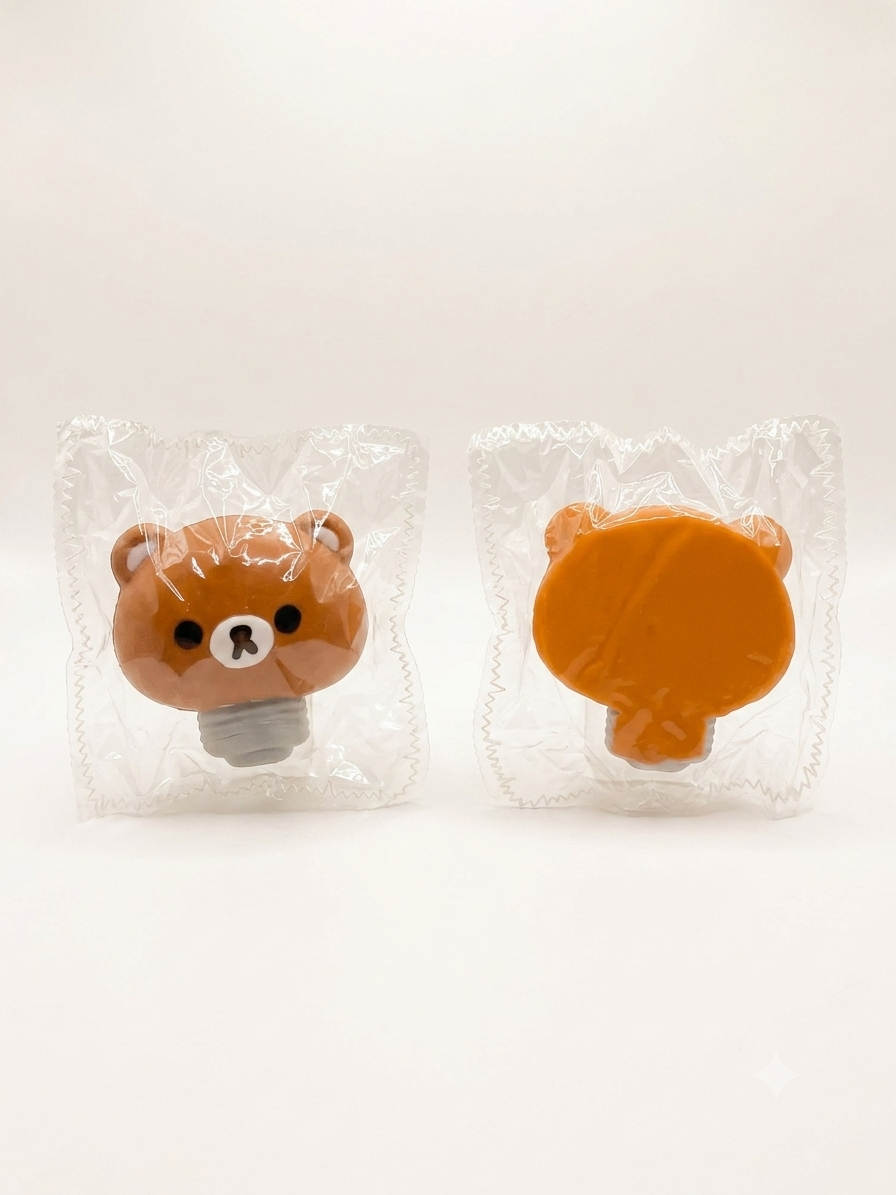 Two small bear-shaped light bulb-shaped accessories in clear plastic packaging, shown from front and back on a plain light background.