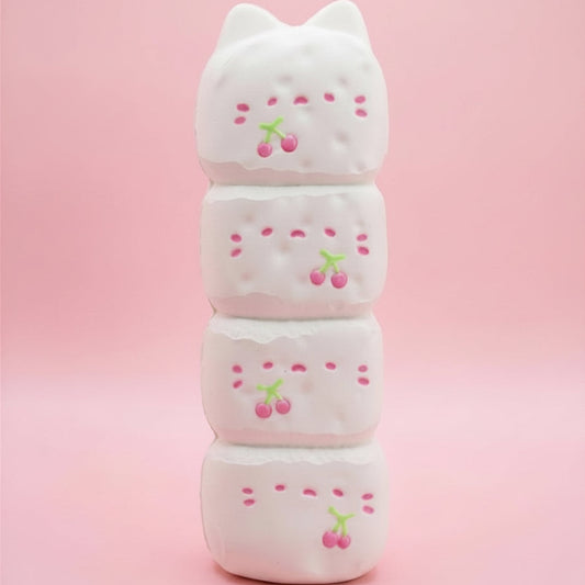 A stack of four white cat-shaped squishy toys with pink cherry details, set against a solid pink background.