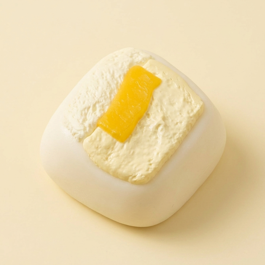A square-shaped white soap bar with a textured pale yellow center and a small bright yellow stripe on top, photographed on a warm cream background.