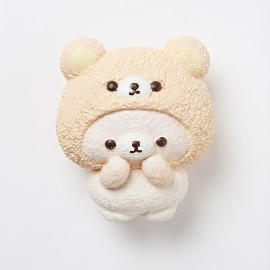 A cute, soft plush toy shaped like a small bear wearing a beige textured hood or hat with a white bear face and hands, centered on a plain white background.