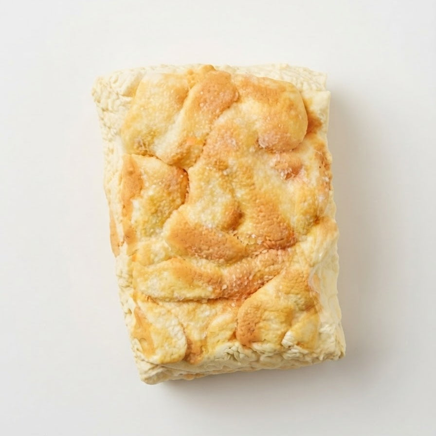 A rectangular piece of golden-brown baked bread or pastry with a flaky, textured surface, photographed from above on a plain white background.