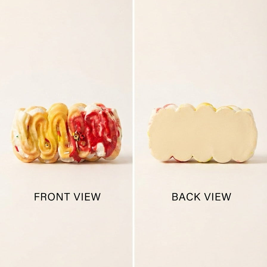 A split-screen product view of a small scalloped cream-colored pastry or cake roll, showing the front view with yellow and red swirled glaze on the left and the back view on the right, labeled 'FRONT VIEW' and 'BACK VIEW' on a plain light background.