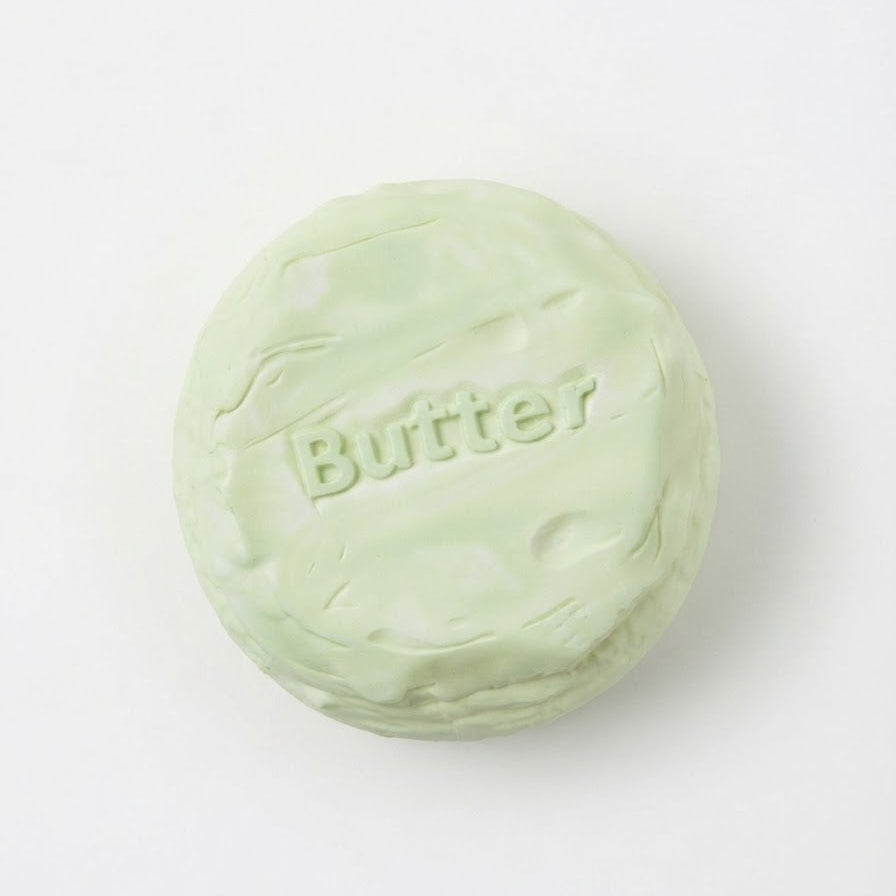 A round, light green bar of soap with the word 'Butter' embossed on the top, photographed from directly above on a clean white background.
