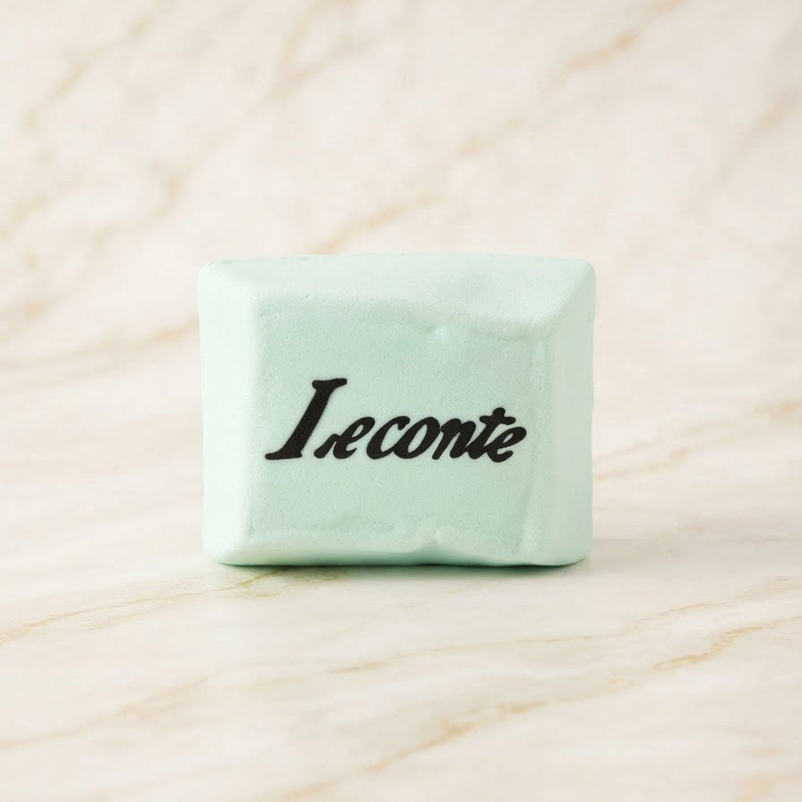 A pale mint green rectangular bar of soap standing upright on a light marble surface, with the black script brand name 'Leconte' printed on the front.