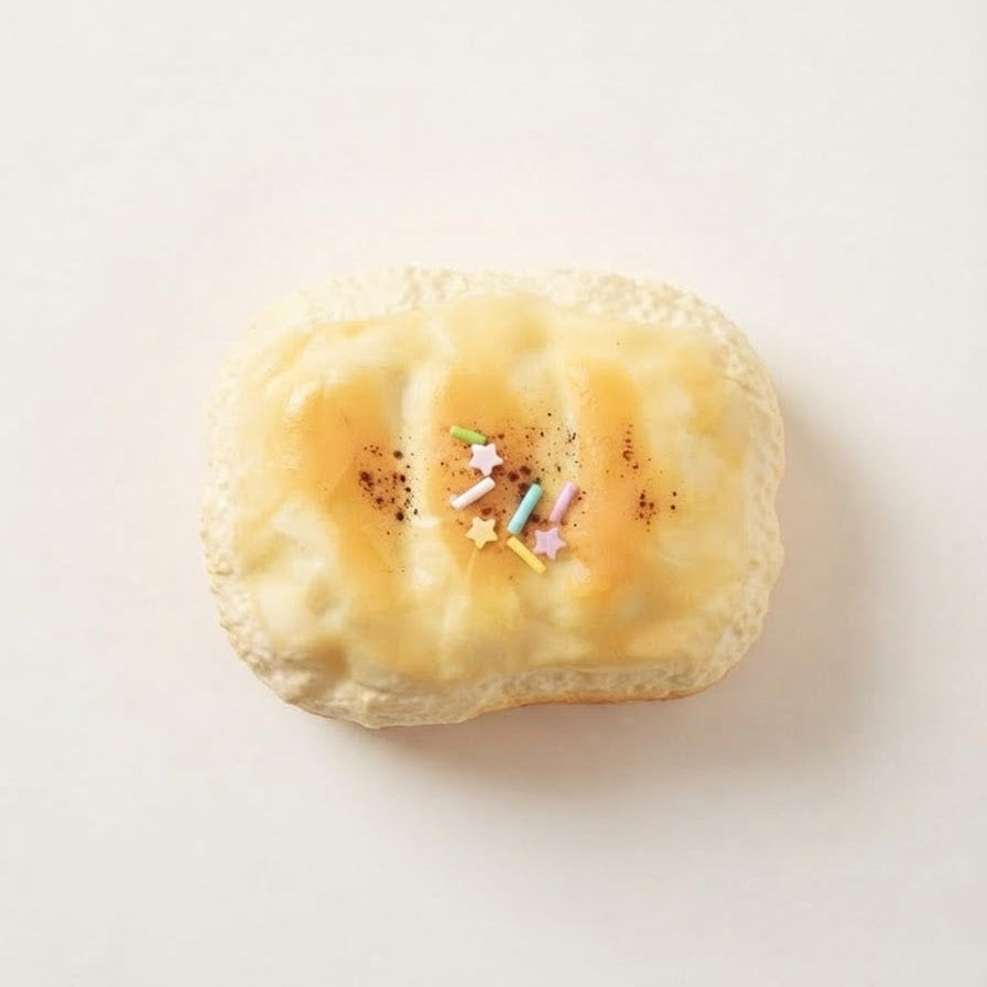 A single baked pastry or bread roll with a golden-brown top and small colorful star sprinkles, photographed on a plain light background.