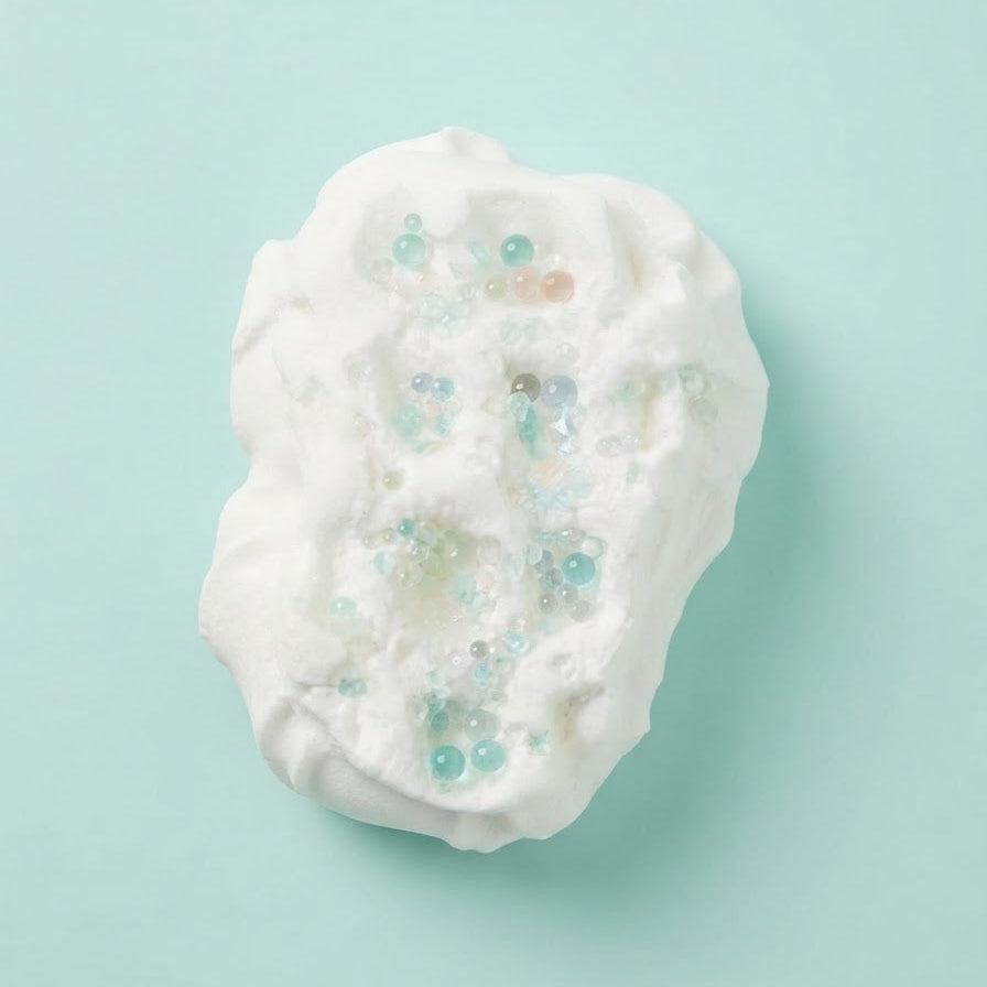 A white, textured, cloud-like product with embedded iridescent blue, green, and peach beads, centered on a solid light aqua background.