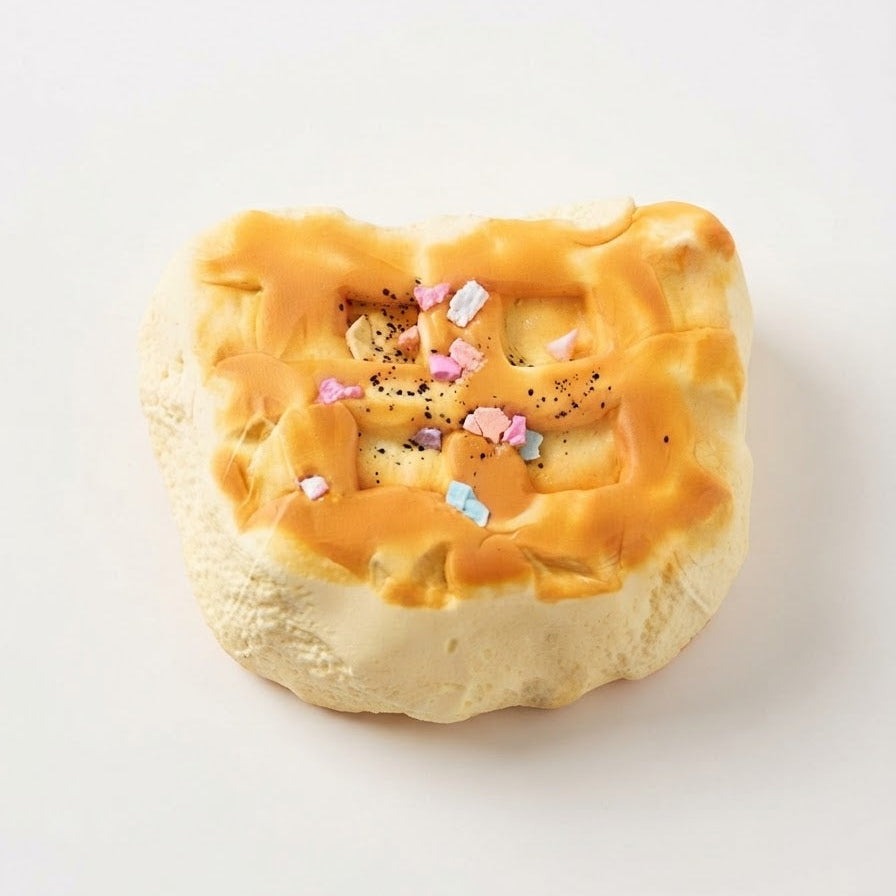 A novelty squishy toy shaped like a piece of toast or a pastry, featuring a textured beige base, golden-brown toasted top, and small pastel sprinkles, photographed on a clean white background.