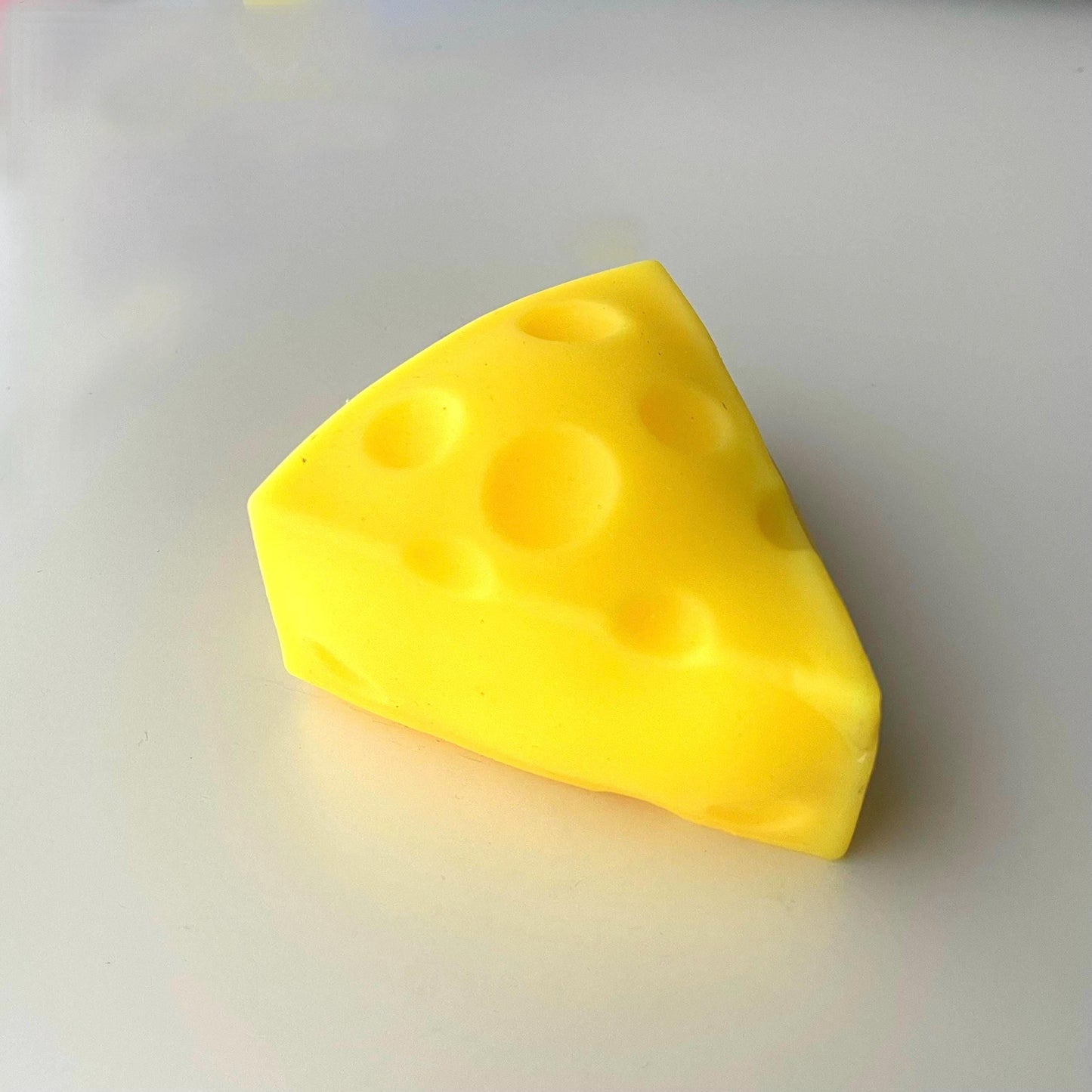 A bright yellow, wedge-shaped cheese. The cheese has several round holes throughout its surface.