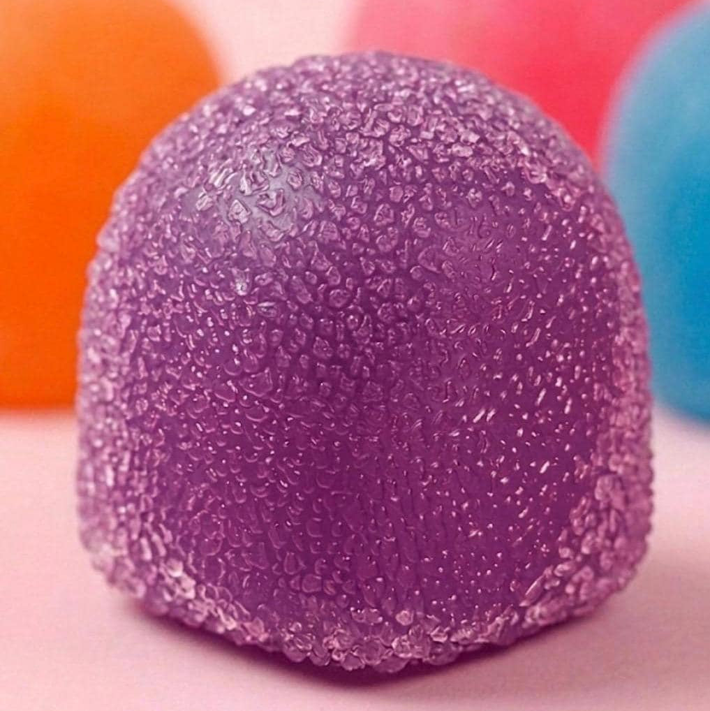 Close-up of a purple textured ball with orange and pink balls in the background.