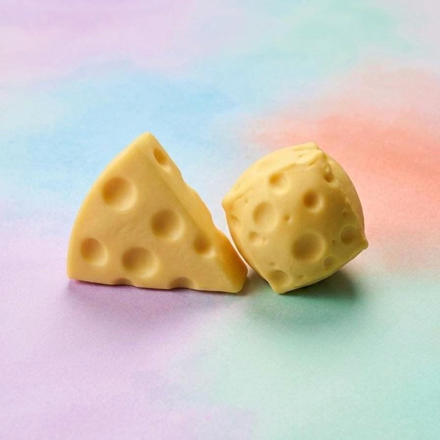 Two pieces of yellow cheese with holes, one triangular and one square, sit on a colorful background. The cheese has a smooth texture and a light yellow color.