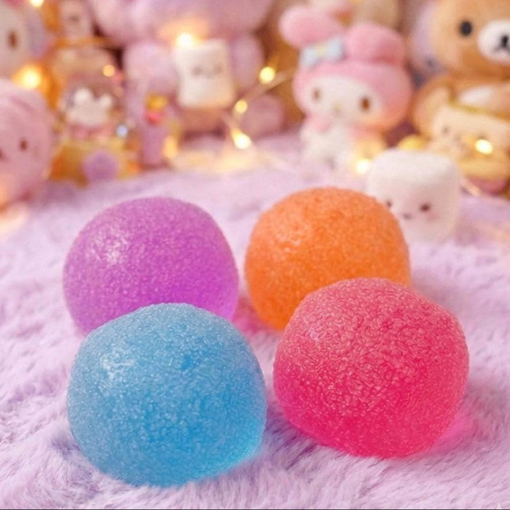 Colorful textured balls on a soft surface with plush toys in the background