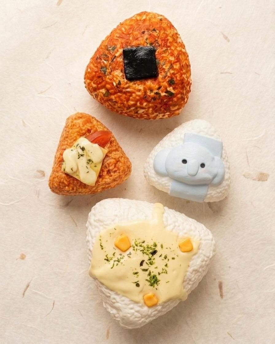 Four toy rocks with different designs on a textured beige surface