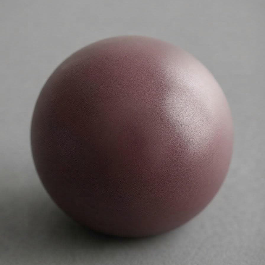 A matte dusty rose or mauve-colored sphere, possibly a ceramic vase, decorative stone, or sculpture, set against a neutral gray background.