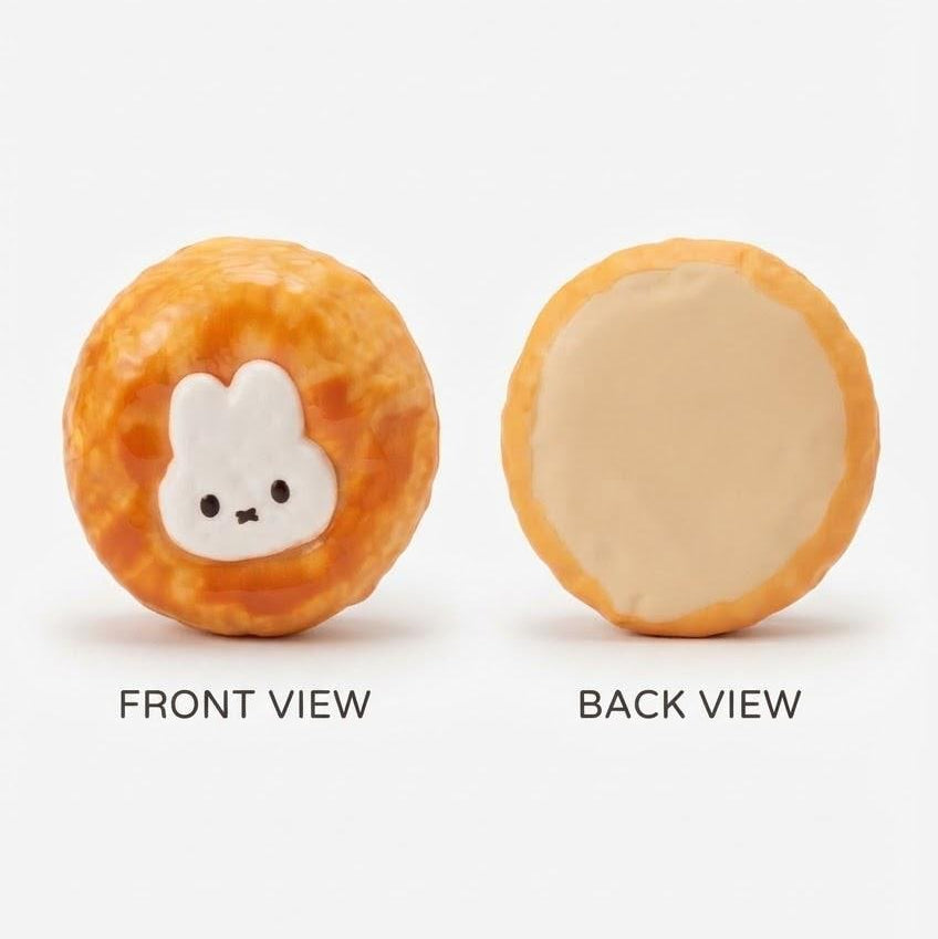 A round, textured orange-brown item shown from front and back on a light gray background. The front view has a white bunny face with small black eyes and a mouth.
